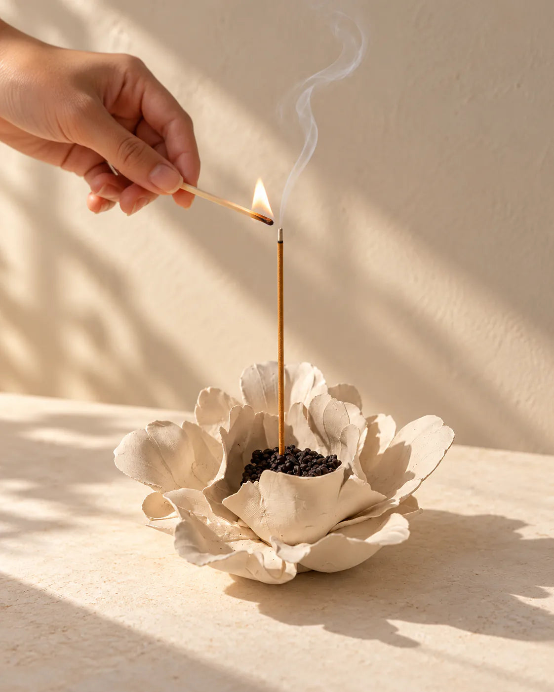 A lit incense stick in a handcrafted flower holder during a quiet ritual